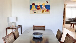 A dining area with a table, chairs, a bowl, a lamp, and a painting on the wall. - The Perch - Lifestyle Yamba (YAMBA)