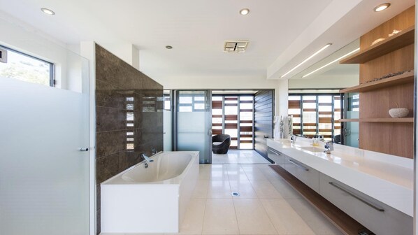 A modern bathroom with a large bathtub, a vanity with a mirror, and a shower area.