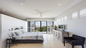 Relax in this inviting bedroom with a large bed, desk, and TV, plus a balcony with a view.