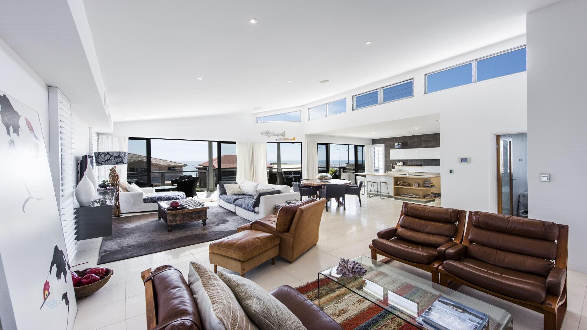 Un espacio habitable amplio con techo alto, ventanas grandes y vista al mar.