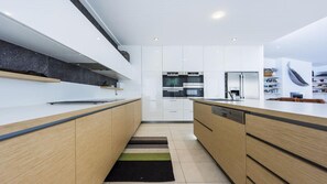 Una cucina moderna con mobili bianchi, un piano di lavoro nero e un pavimento in legno.