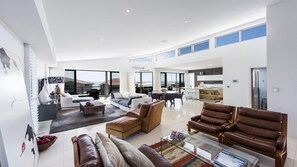 Relax in this open-plan living space with a high ceiling and large windows, featuring a comfortable seating area and dining space.