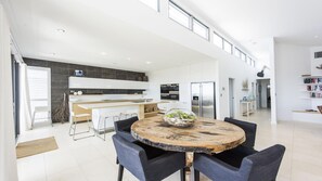 Una cucina moderna con mobili bianchi, un'isola centrale e un'area pranzo con un tavolo rotondo e sedie.
