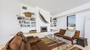 Relax in this stylish living room with a cozy fireplace, comfortable seating, and a natural touch from the driftwood wall feature.