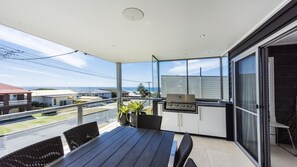 Enjoy ocean views from this balcony with a table, chairs, grill, and lush greenery.