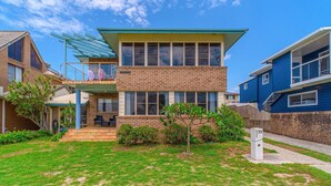A two-story residential building with a balcony, a brick facade, and a well-maintained lawn. - Sandilands 2 - Lifestyle Yamba (YAMBA)