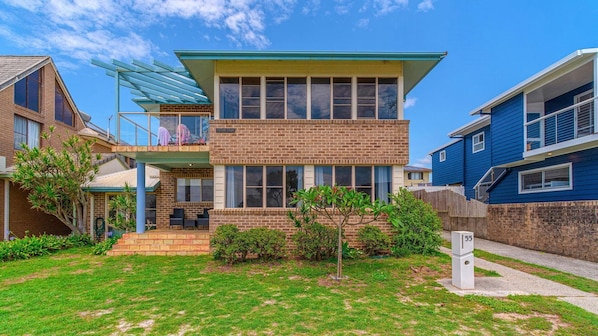 A two-story residential building with a balcony, a brick facade, and a well-maintained lawn.