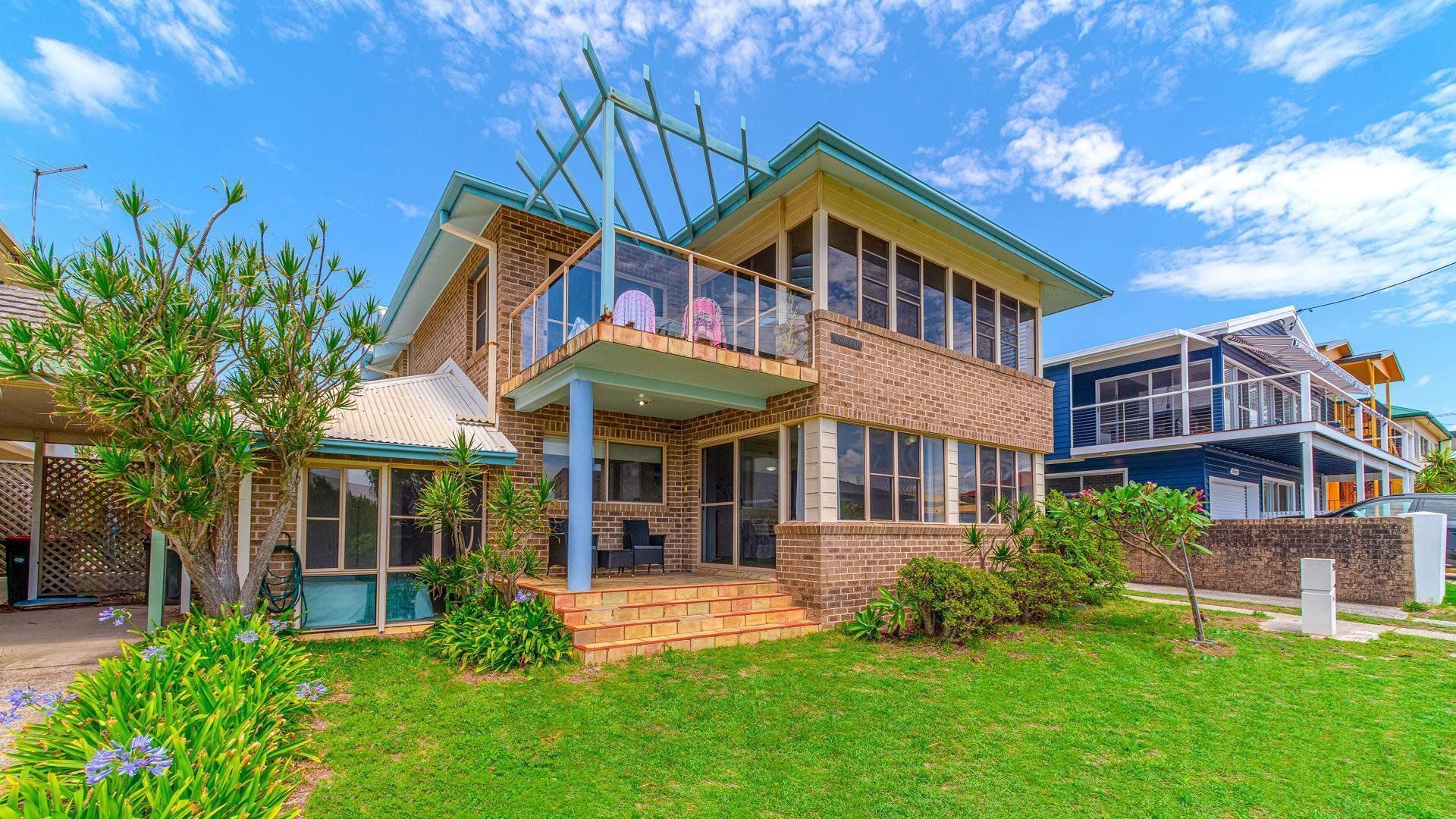 A two-story house with a balcony, a covered porch, and a well-maintained lawn.