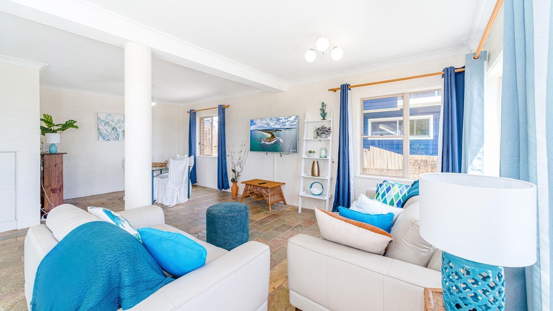 A spacious living room with a sofa set, a dining area, and a view of the outside.