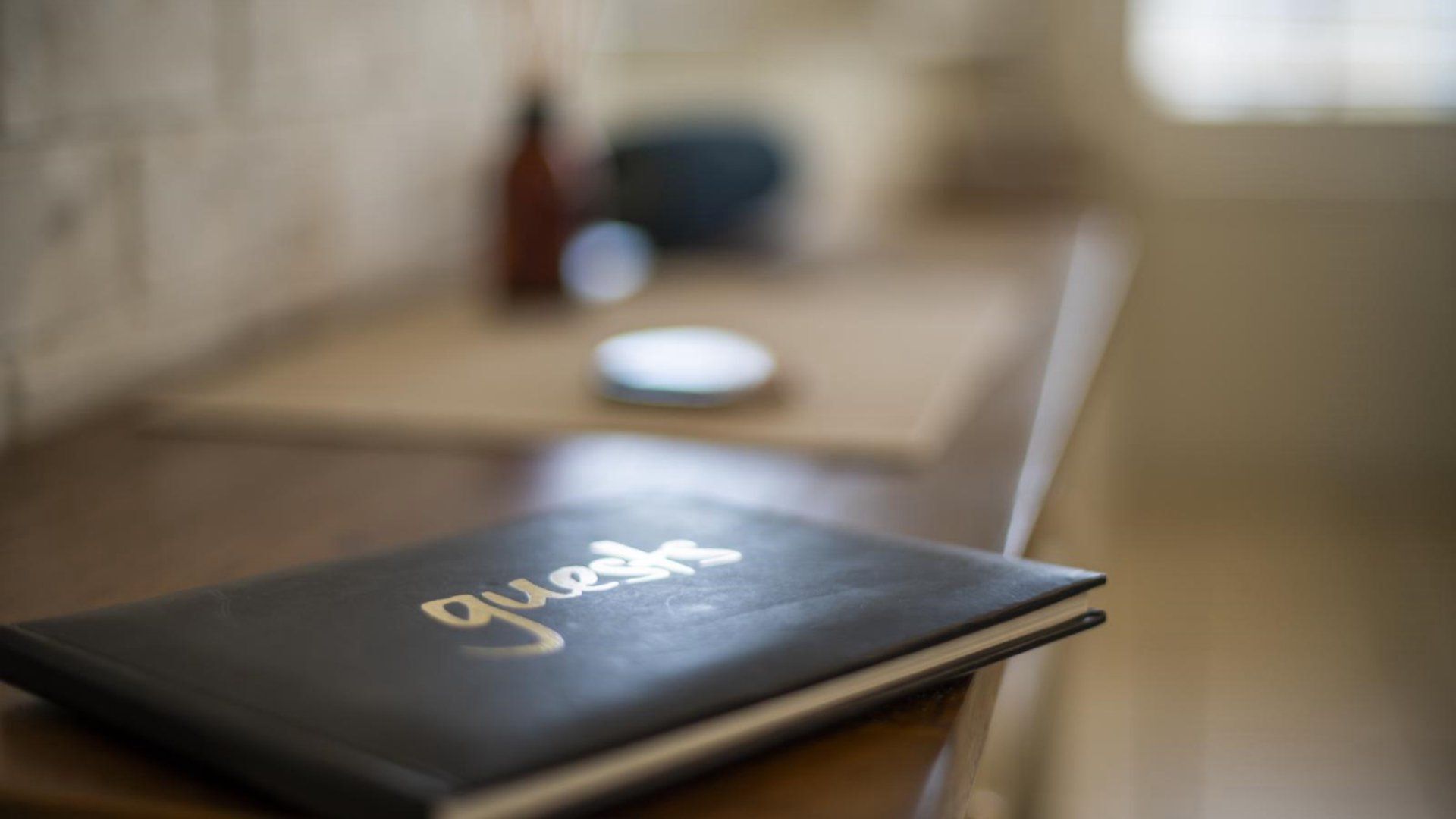 A notebook with the word 'guests' on the cover, placed on a wooden surface.