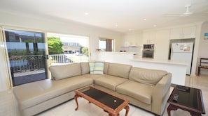 Relax in this spacious living area with a sofa, side table, and kitchenette, offering a balcony with a view of the surrounding greenery.