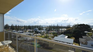 Enjoy a peaceful view of the surrounding residential area from this balcony with a glass railing and outdoor seating.
