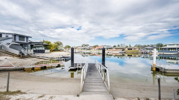 Un port de plaisance avec une jetée donnant sur une étendue d’eau calme, entouré d’immeubles résidentiels et sous un ciel dégagé.