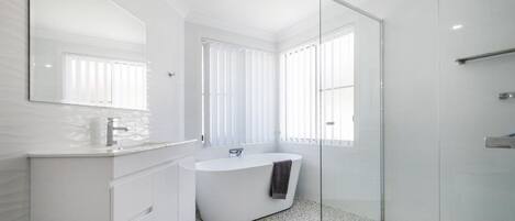 A modern bathroom with a freestanding bathtub, a glass shower enclosure, and a large mirror.