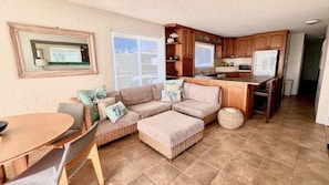 A cozy living area with a sofa, ottoman, and a dining table. - Suncrest 4 - Lifestyle Yamba (YAMBA)