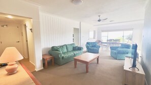 A living room with a green sofa, a wooden coffee table, and a blue armchair.