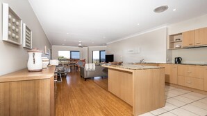 Une cuisine moderne avec des meubles en bois, un îlot central et un coin repas offrant une vue agréable.