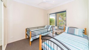 A bedroom with a single bed, a smaller bed, and a desk with a lamp. - The Sands Unit 59 - Lifestyle Yamba (YAMBA)