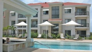 Un hôtel doté d’une piscine, d’un espace extérieur aménagé et d’un toit recouvert de tuiles rouges.