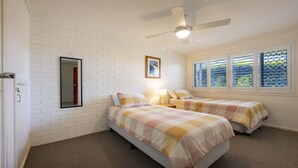 A bedroom with two beds, a ceiling fan, a window with blinds, and a door. - Lighthouse Unit 2 - Lifestyle Yamba (YAMBA)