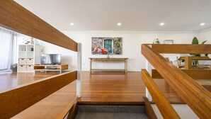 Una sala de estar moderna con una escalera de madera, un televisor de pantalla plana y un cuadro de una moto.