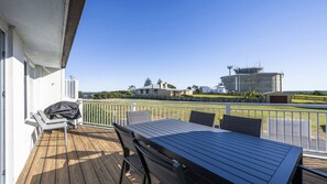 A deck with a table and chairs, overlooking a fenced area with buildings and a large cylindrical structure.