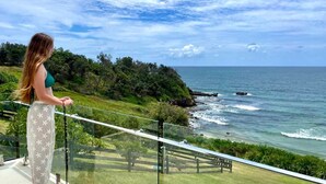 Une personne qui contemple un paysage côtier, avec vue sur la mer et la végétation.