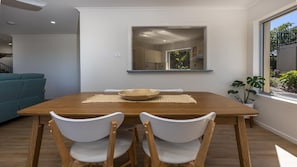 A dining area with a wooden table, white chairs, and a woven placemat.