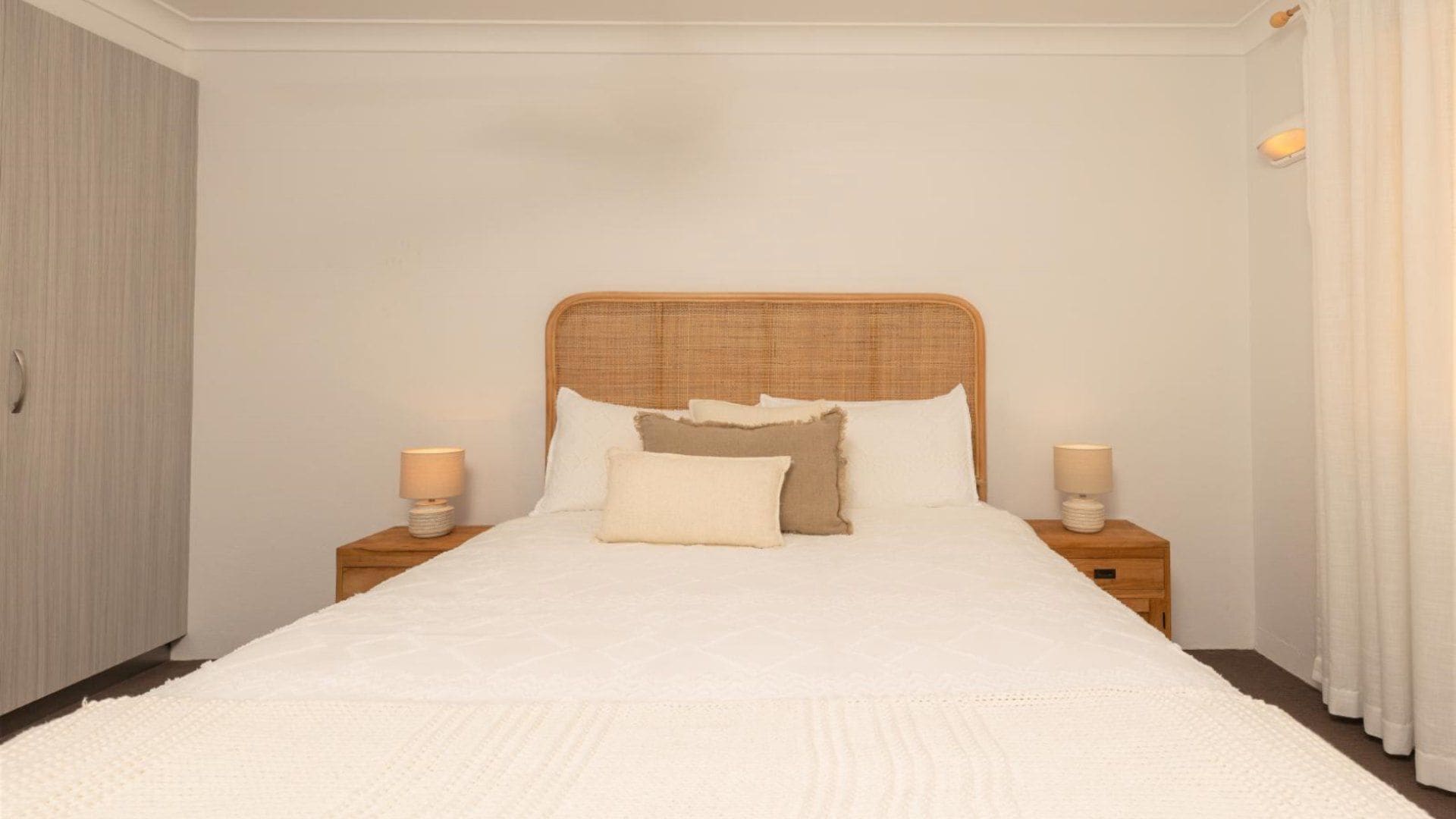 A bedroom with a large bed, two bedside tables, and a wardrobe.