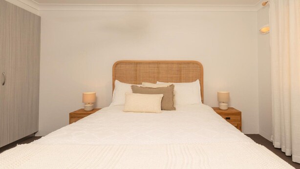 Een slaapkamer met een groot bed, twee nachtkastjes en een garderobe.