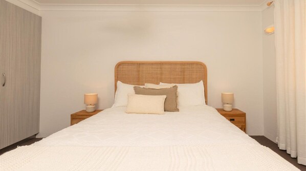 A bedroom with a large bed, two bedside tables, and a wardrobe.