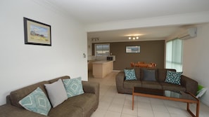 Relax in this stylish living room with a sofa, coffee table, and dining area, offering a view from the window.