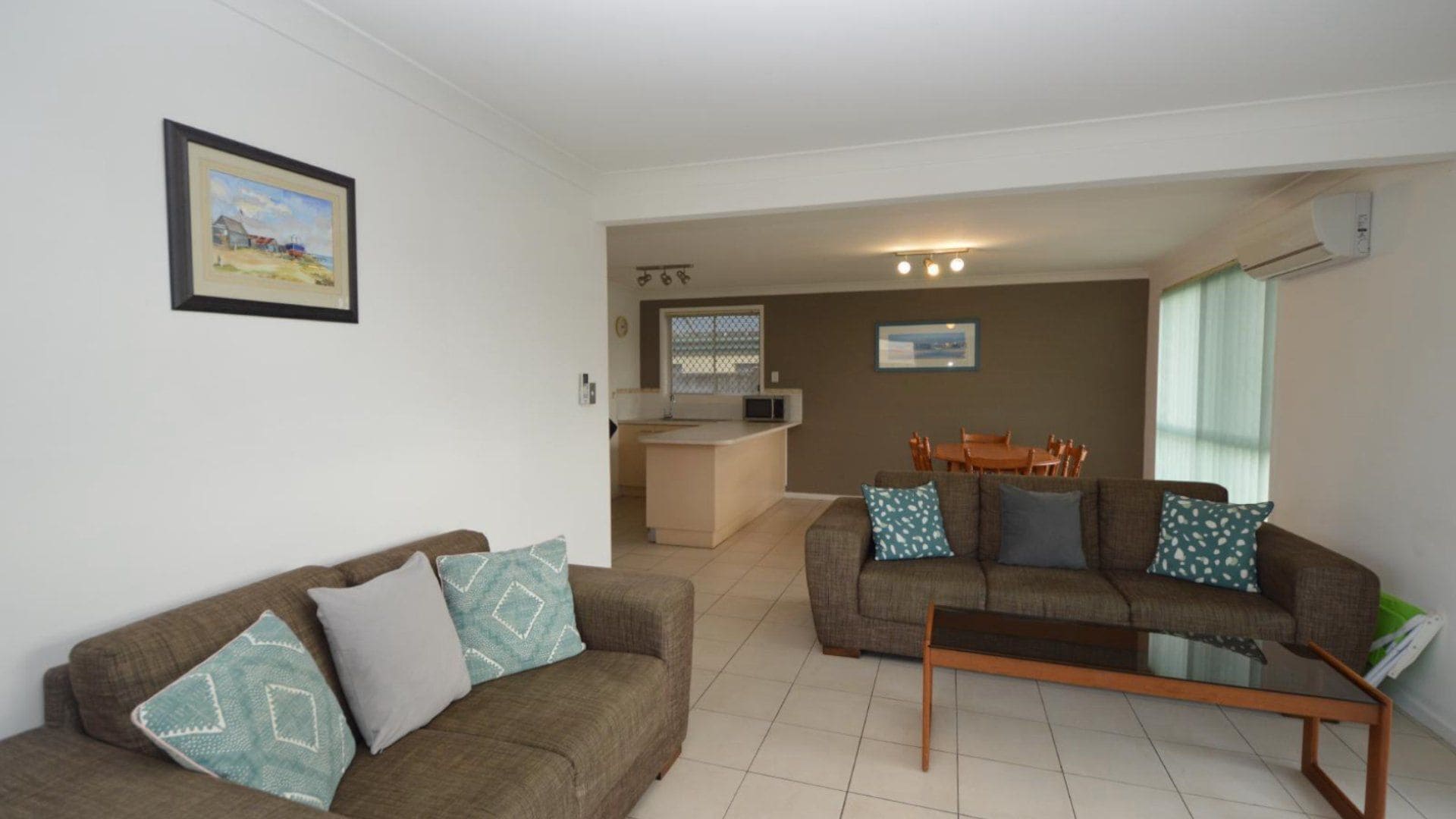 A living room with two sofas, a coffee table, a dining area with a table and chairs, and a kitchen area with a microwave.