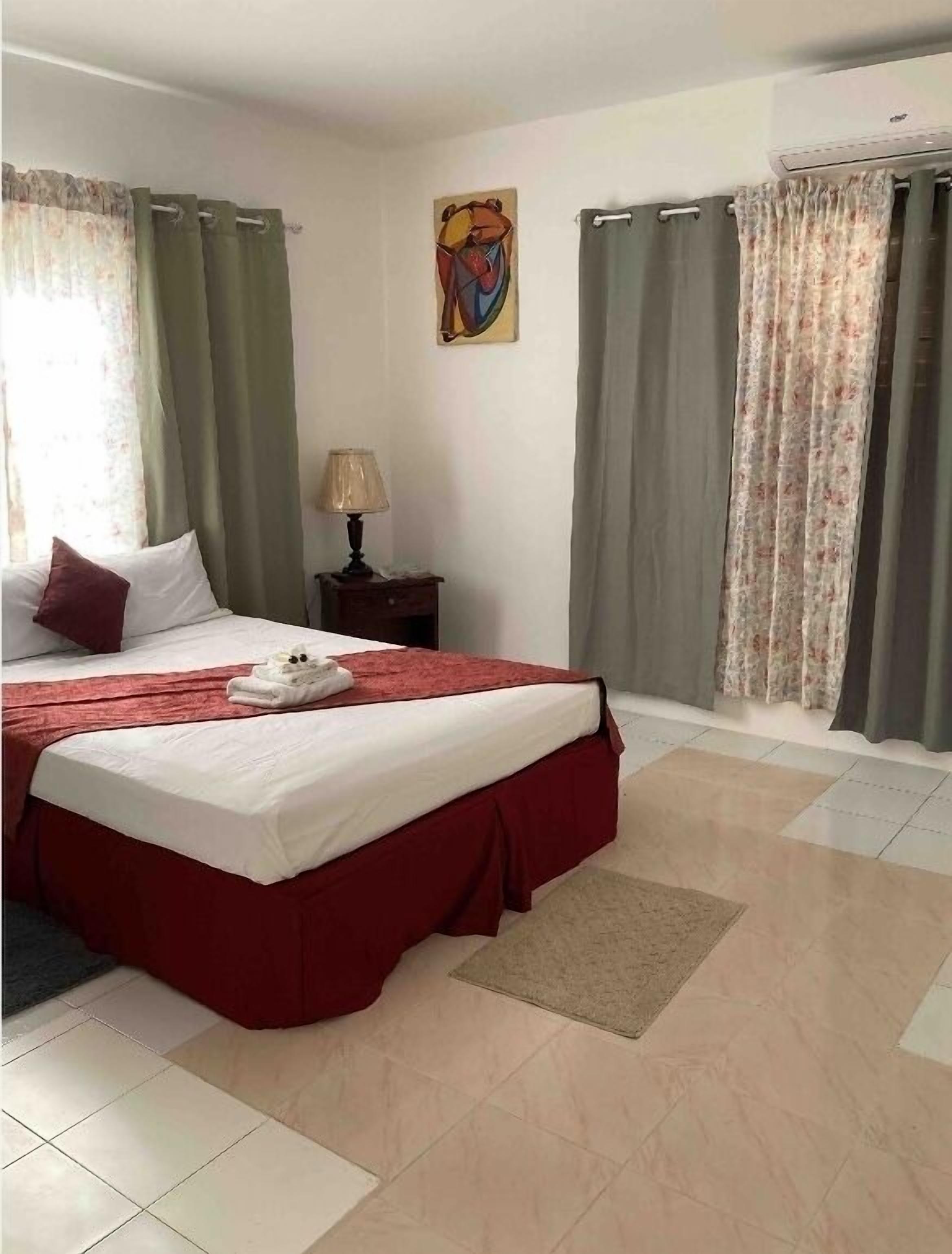 A hotel room with a large bed, a nightstand with a lamp, and a painting on the wall.