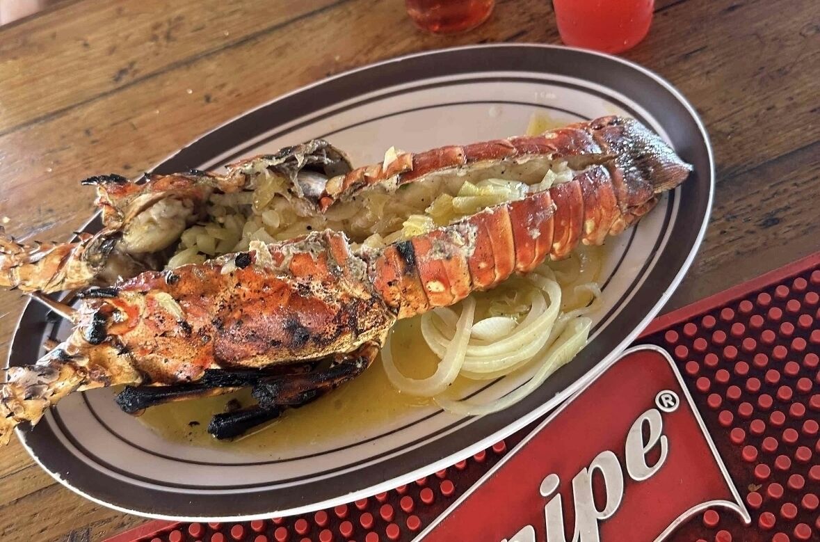 A lobster tail on a plate with a red and white logo.