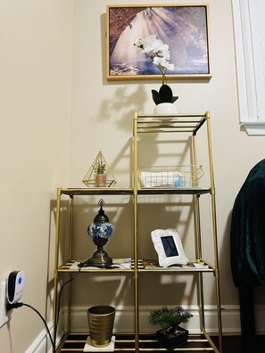 Organized corner with a multi-tiered storage unit, featuring a vase with a flower arrangement and decorative items.