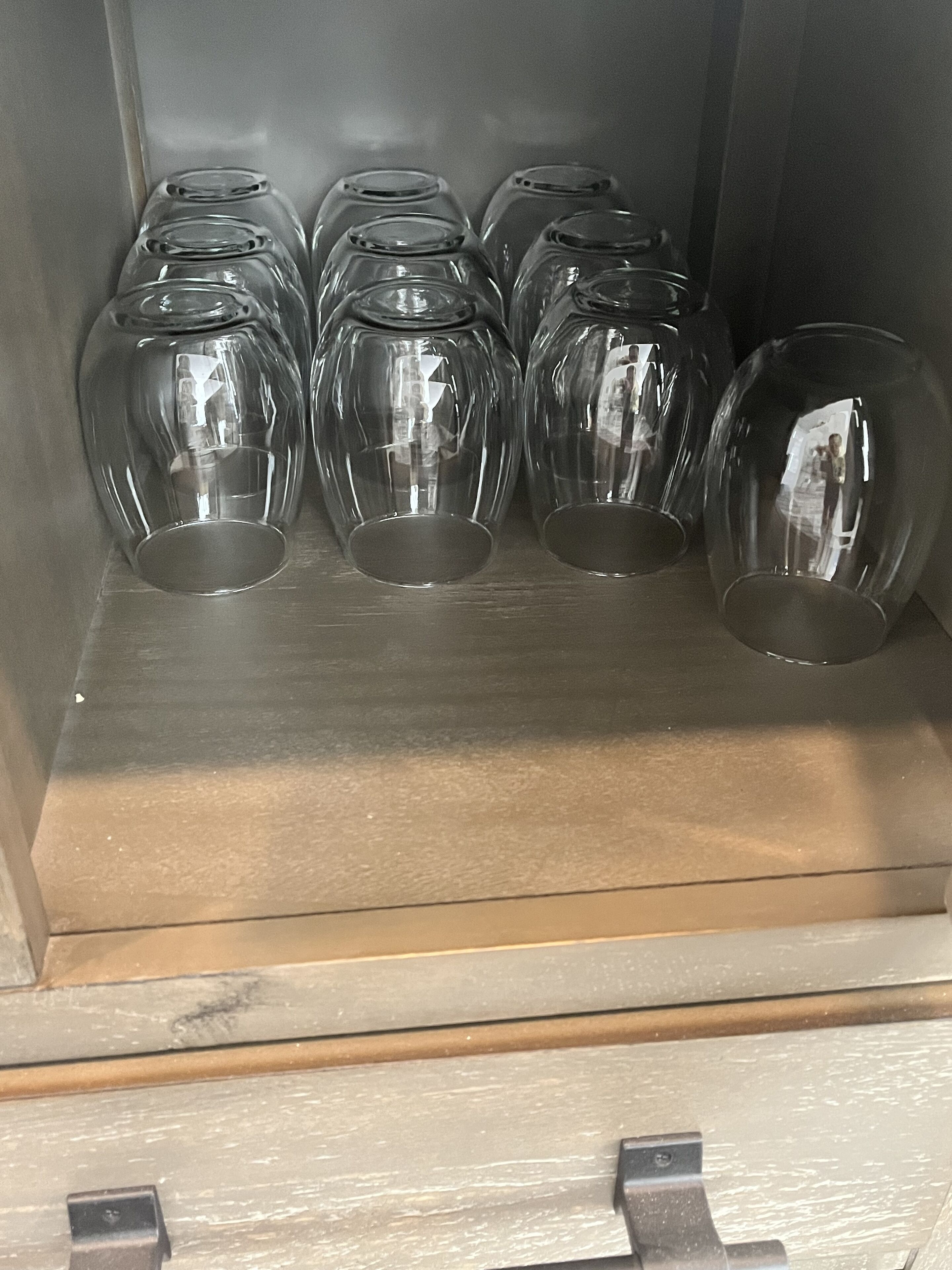 Un área de almacenamiento con estantes llenos de vasos de vidrio transparentes.