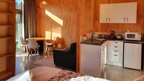 A modern, compact living space with a kitchenette, a dining area, and a sofa.