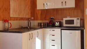 A modern kitchen with white cabinets, a stainless steel refrigerator, and a microwave on the countertop.