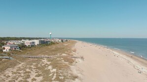 Una playa con un paseo marítimo que lleva a un conjunto de edificios.