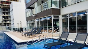 Une piscine sur le toit, dotée de chaises longues et d’une balustrade en verre.