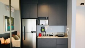 Une cuisine moderne avec des meubles de couleur sombre, un réfrigérateur en acier inoxydable, un four à micro-ondes et une machine à café.