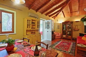 A cozy dining area with wooden beams, a dining table set with plates, glasses, and a bottle, and a red rug.