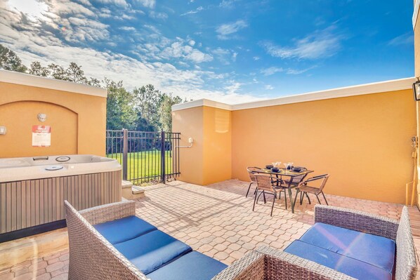 Un patio con jacuzzi, mobiliario de mimbre y una mesa con sillas.