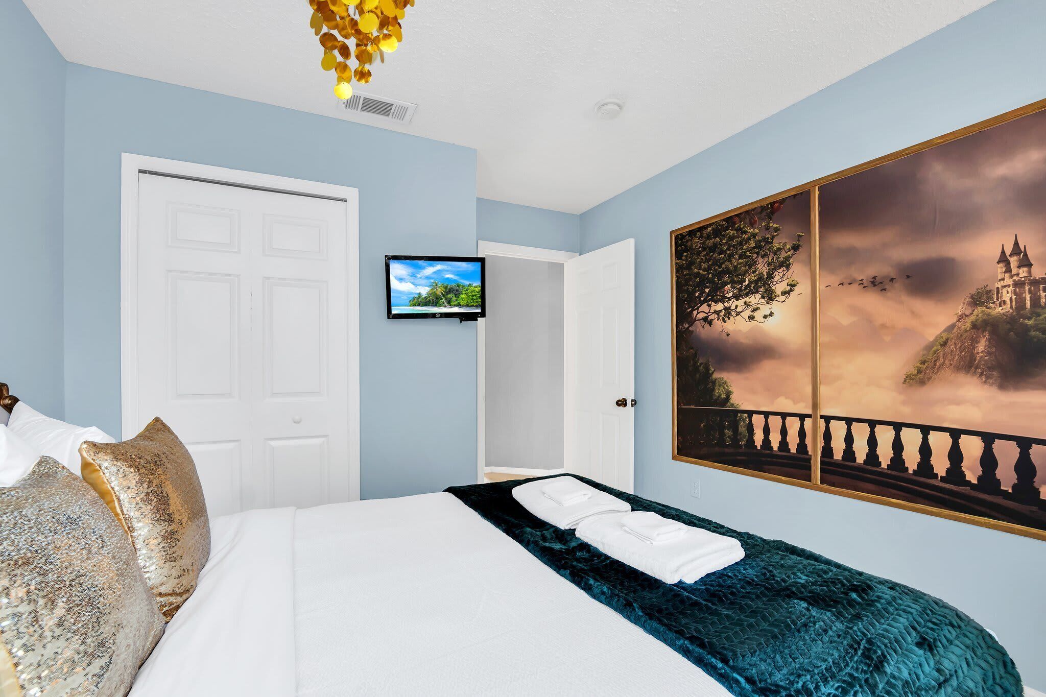 A hotel room with a bed, a TV, and a large scenic wall mural.