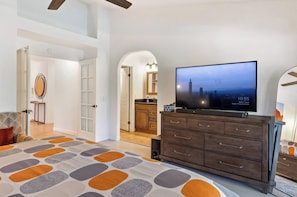 A modern living room with a large flat-screen TV, a wooden cabinet, and a patterned rug.
