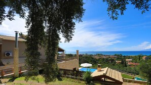 Una villa con piscina, vistas al mar y un jardín exuberante.
