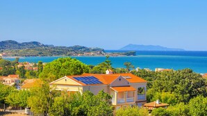 Un pueblo costero con casas equipadas con paneles solares, rodeado de abundante vegetación y un mar azul cristalino.