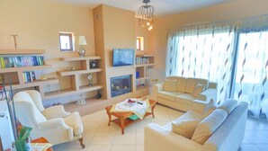 Una sala de estar con sofá, sillones, televisor y chimenea.