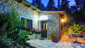 Une maison en pierre avec un patio carrelé, une porte et une fenêtre.